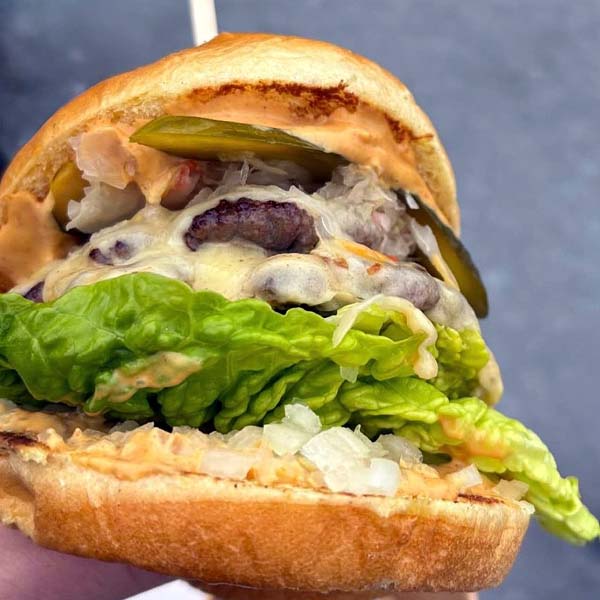 Double smash burger stacked with melted cheese, pickles, onion, and secret sauce in a brioche bun, served street food style.