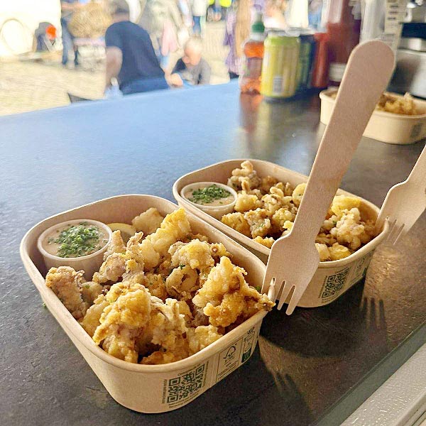 Spiced crispy squid street food served on The Clippy’s vintage bus counter in Plymouth, garnished with herbs and lemon.